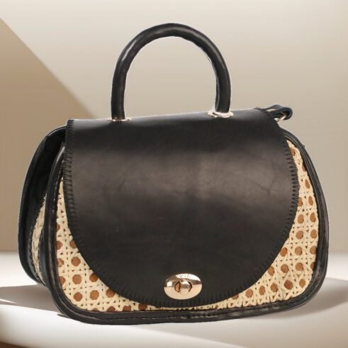 Chic handbag with black leather and woven cane accents, featuring a stylish round shape and gold clasp closure against a soft neutral background.