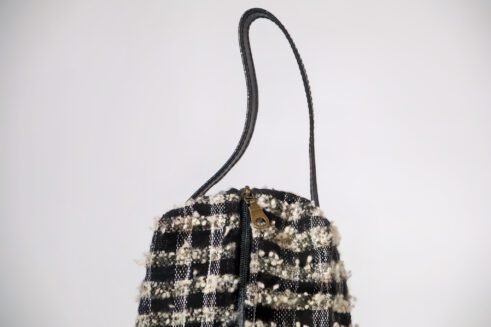 Black and white textured pouch with handle and zipper closure, perfect for organizing cosmetics and small essentials.