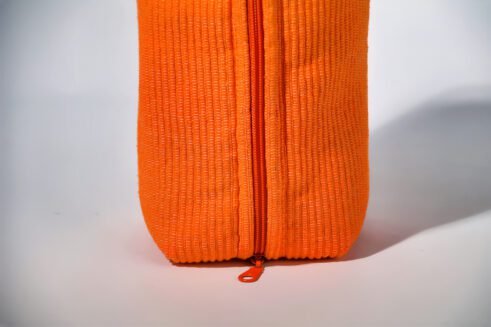 Orange cosmetic pouch with textured fabric and zipper, perfect for storing cosmetics and toiletries.