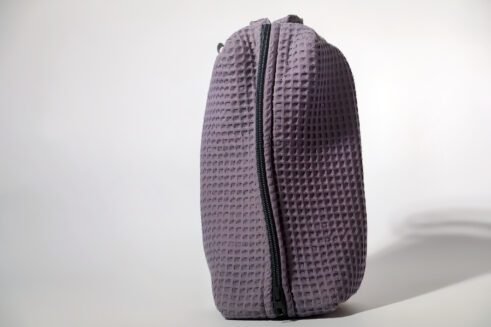Gray textured pouch with handle and zipper closure, perfect for organizing cosmetics and small items.