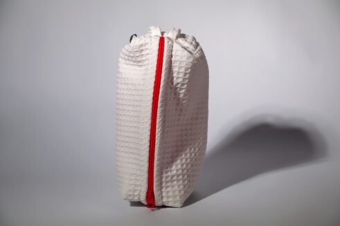 Stylish white cosmetic pouch with a bold red zipper, ideal for storing toiletries and beauty products.