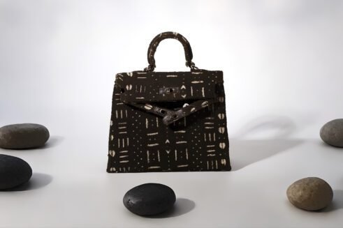 A Moroccan handcrafted tote bag with a bold abstract print, placed on a neutral background surrounded by small rocks, emphasizing its unique design and artistic charm.