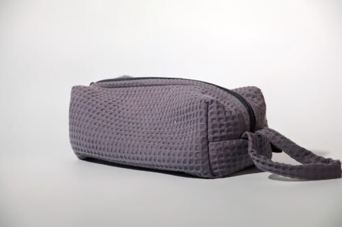 Gray textured pouch with handle and zipper closure, perfect for organizing cosmetics and small items.