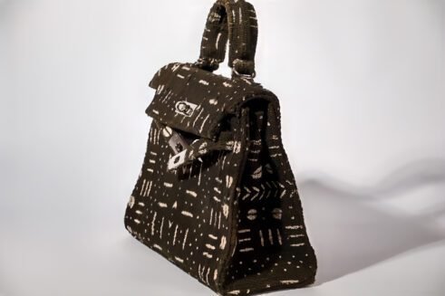 A Moroccan handcrafted tote bag with a bold abstract print, placed on a neutral background surrounded by small rocks, emphasizing its unique design and artistic charm.