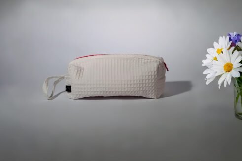 Stylish white cosmetic pouch with a bold red zipper, ideal for storing toiletries and beauty products.
