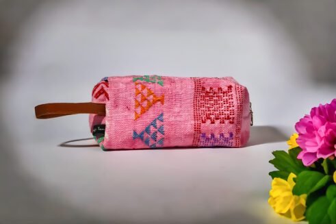 Colorful pink cosmetic pouch with geometric patterns and a small handle.