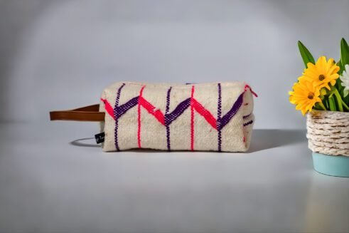 Moroccan-inspired pouch with a colorful pink and purple zig-zag design, featuring a handle and secure zipper closure.