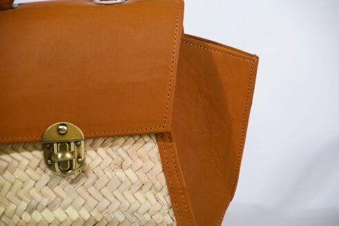 A stylish, handcrafted leather and woven material backpack with a brass clasp, set against a neutral background with a modern and elegant feel.