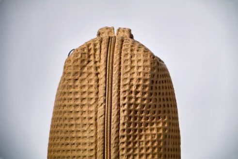 Beige textured pouch with a leather handle, perfect for organizing small essentials with a practical and stylish design.