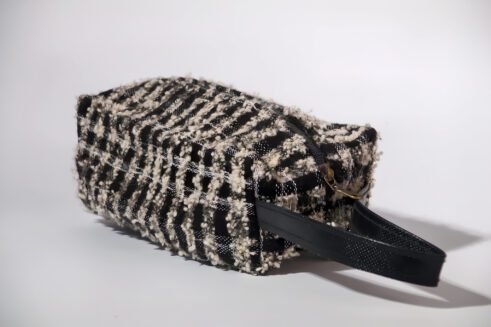 Black and white textured pouch with handle and zipper closure, perfect for organizing cosmetics and small essentials.