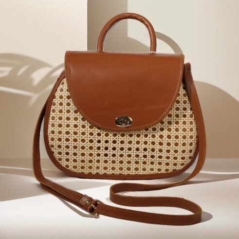 Elegant handbag with leather handles and woven cane material, showcasing a sleek and timeless design against a soft neutral background.