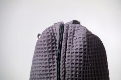 Gray textured pouch with handle and zipper closure, perfect for organizing cosmetics and small items.