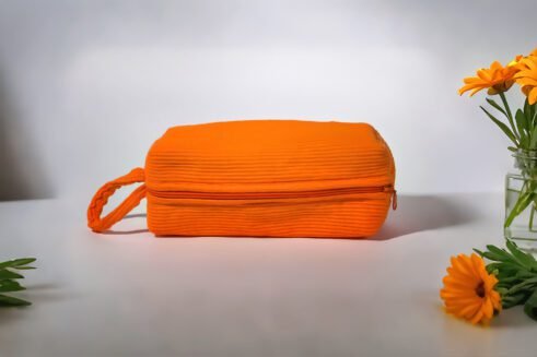 Orange cosmetic pouch with textured fabric and zipper, perfect for storing cosmetics and toiletries.