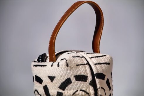 A black and white Moroccan-inspired geometric pouch with a leather handle, perfect for storing essentials in style.