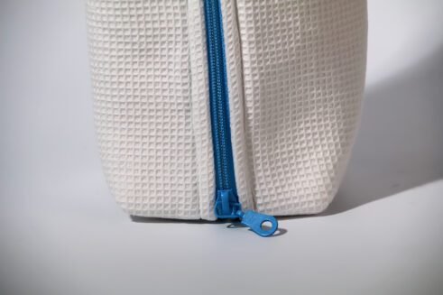 White waffle weave cosmetic pouch with a blue zipper, designed for travel and everyday use.