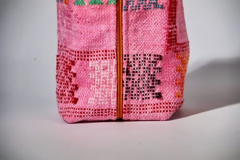 Colorful pink cosmetic pouch with geometric patterns and a small handle.