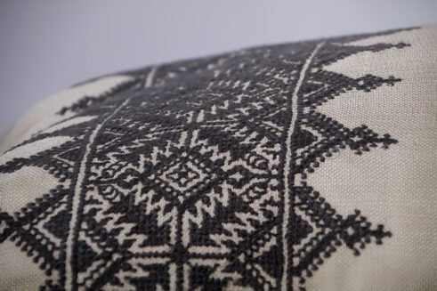 Gray Moroccan pillow with black embroidered geometric design and tassels