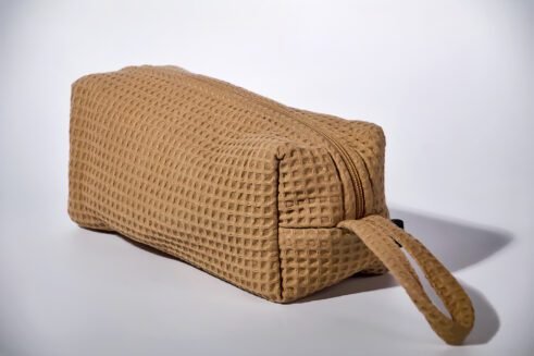 Beige textured pouch with a leather handle, perfect for organizing small essentials with a practical and stylish design.