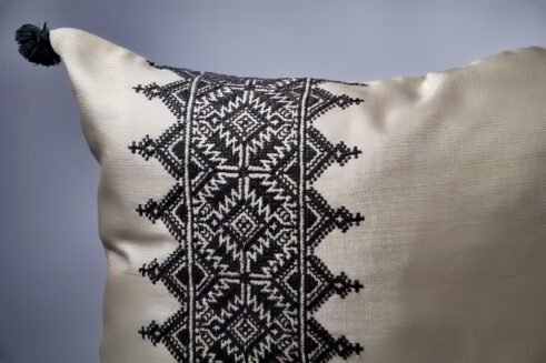 Gray Moroccan pillow with black embroidered geometric design and tassels
