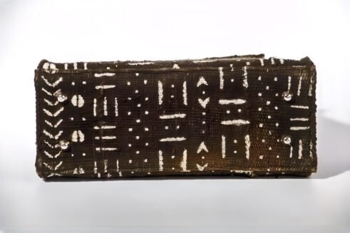 A Moroccan handcrafted tote bag with a bold abstract print, placed on a neutral background surrounded by small rocks, emphasizing its unique design and artistic charm.