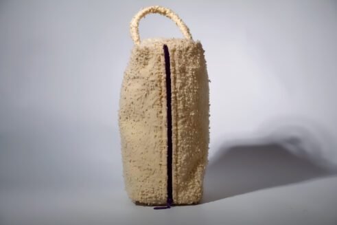 Beige textured pouch with a leather handle, featuring a secure zipper closure, perfect for organizing small essentials with a chic and functional design.