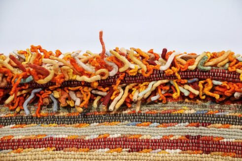 Handwoven vibrant orange Moroccan wool rug with a unique textured design, perfect for adding warmth and style to any room