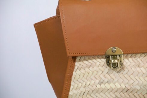 A stylish, handcrafted leather and woven material backpack with a brass clasp, set against a neutral background with a modern and elegant feel.