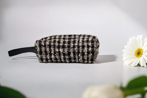 Black and white textured pouch with handle and zipper closure, perfect for organizing cosmetics and small essentials.