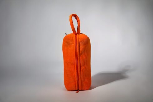 Orange cosmetic pouch with textured fabric and zipper, perfect for storing cosmetics and toiletries.
