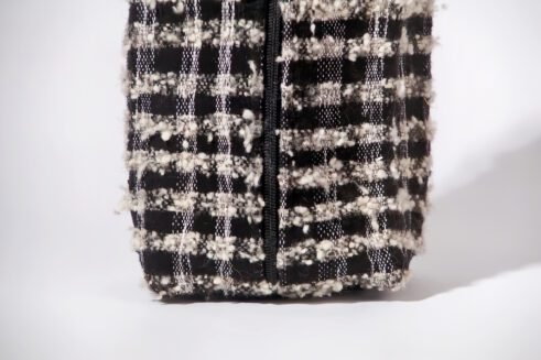 Black and white textured pouch with handle and zipper closure, perfect for organizing cosmetics and small essentials.