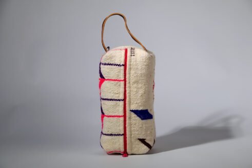 Moroccan-inspired pouch with a colorful pink and purple zig-zag design, featuring a handle and secure zipper closure.