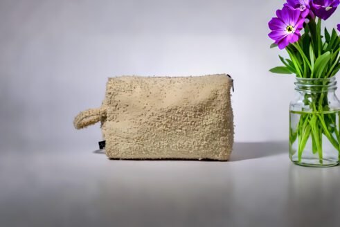 Beige textured pouch with a leather handle, featuring a secure zipper closure, perfect for organizing small essentials with a chic and functional design.