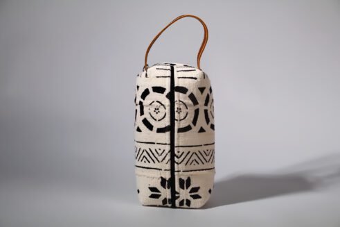 A black and white Moroccan-inspired geometric pouch with a leather handle, perfect for storing essentials in style.