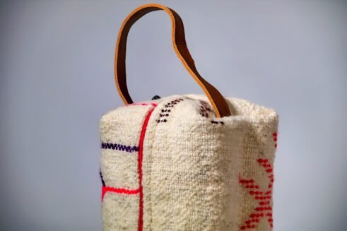 Moroccan-inspired pouch with a colorful pink and purple zig-zag design, featuring a handle and secure zipper closure.