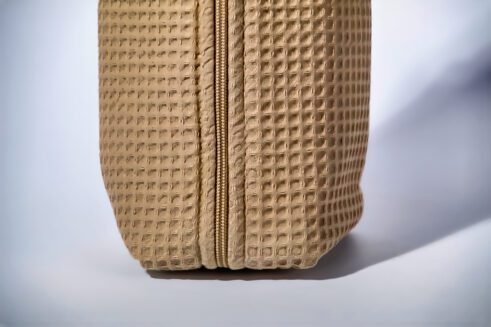 Beige textured pouch with a leather handle, perfect for organizing small essentials with a practical and stylish design.