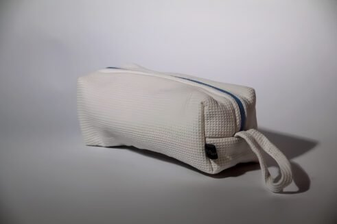 White waffle weave cosmetic pouch with a blue zipper, designed for travel and everyday use.