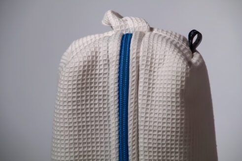 White waffle weave cosmetic pouch with a blue zipper, designed for travel and everyday use.