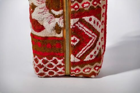 Handcrafted floral cosmetic pouch with a sturdy handle and vibrant red, brown, and cream patterns.