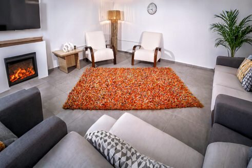 Handwoven vibrant orange Moroccan wool rug with a unique textured design, perfect for adding warmth and style to any room