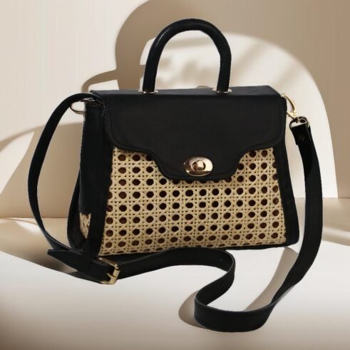 Chic handbag with a black leather top and woven cane body, featuring a gold-tone clasp, a sturdy handle, and an adjustable shoulder strap, styled against a soft neutral backdrop.