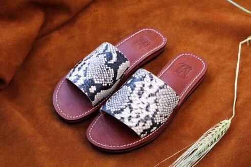 Moroccan handmade slide sandals with a black-and-white python print leather upper and a sculpted black rubber sole.