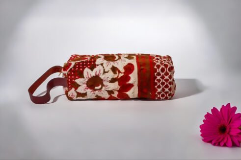 Handcrafted floral cosmetic pouch with a sturdy handle and vibrant red, brown, and cream patterns.