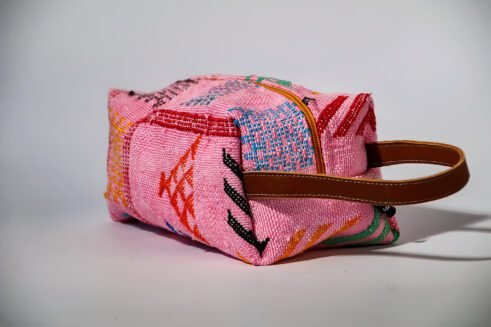 Colorful pink cosmetic pouch with geometric patterns and a small handle.