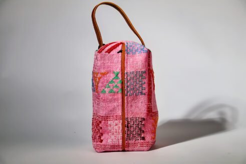 Colorful pink cosmetic pouch with geometric patterns and a small handle.