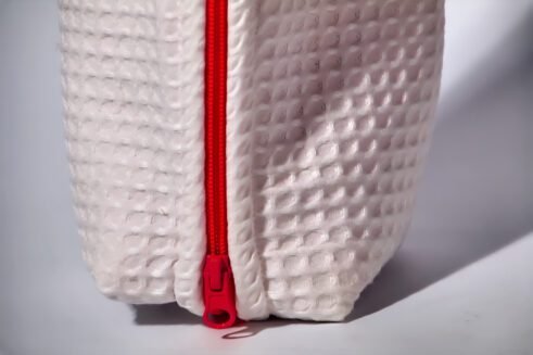 Stylish white cosmetic pouch with a bold red zipper, ideal for storing toiletries and beauty products.