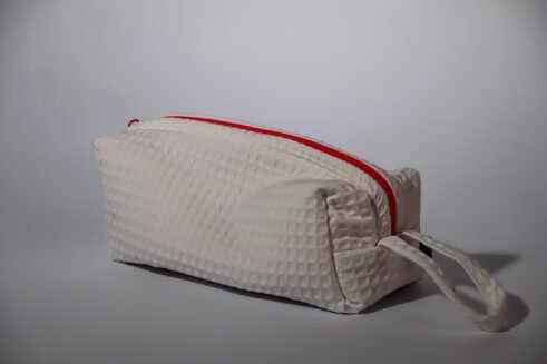 Stylish white cosmetic pouch with a bold red zipper, ideal for storing toiletries and beauty products.