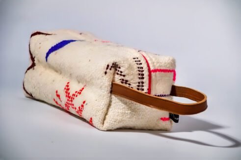 Moroccan-inspired pouch with a colorful pink and purple zig-zag design, featuring a handle and secure zipper closure.